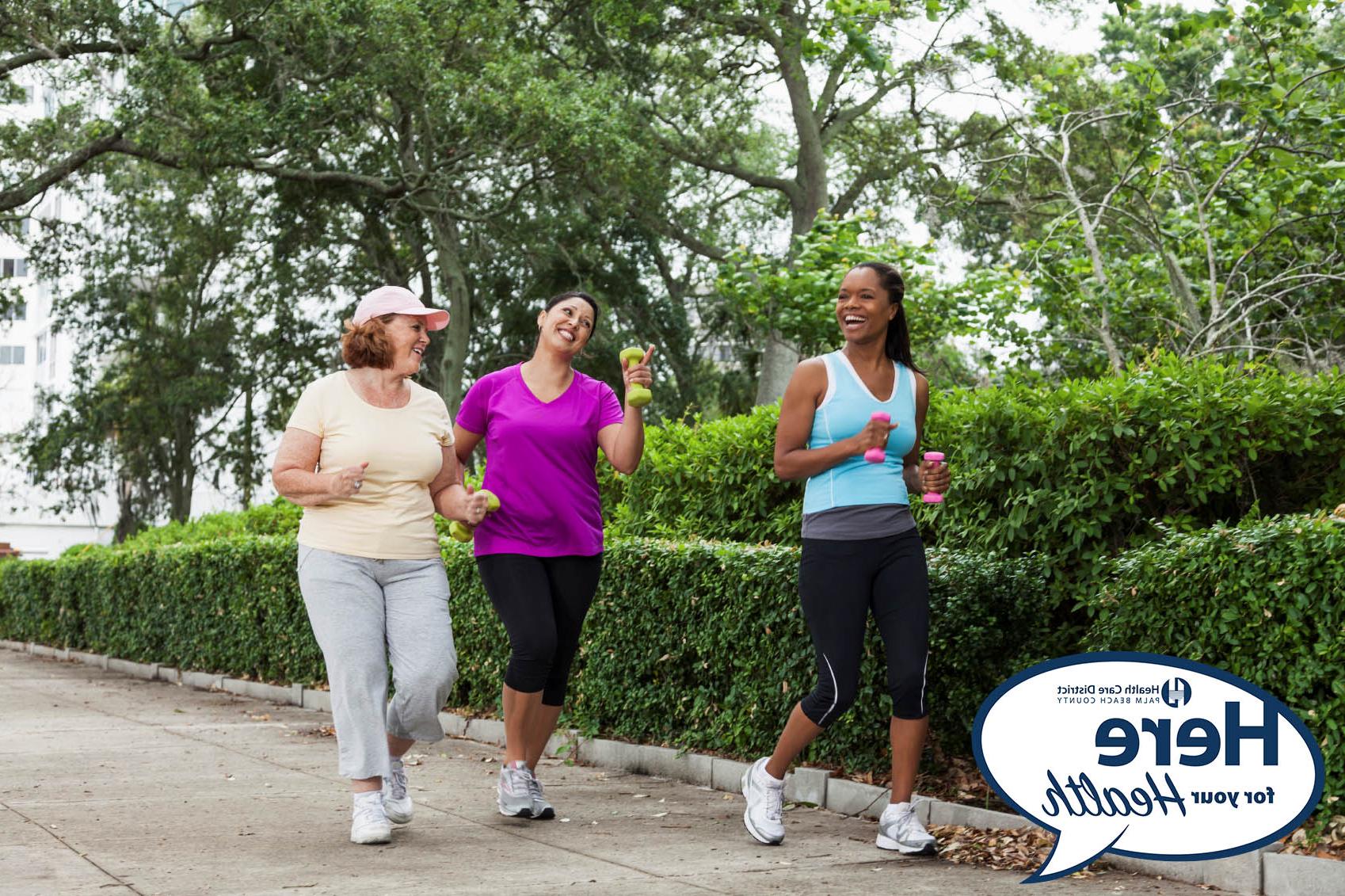 Three women having a happy conversation while jogging with dumbbells